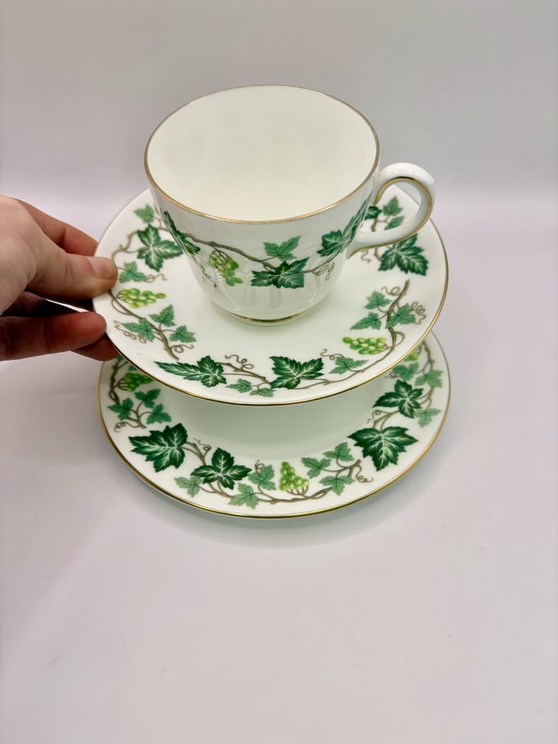 Teacup and saucers with green leaf pattern on a white background