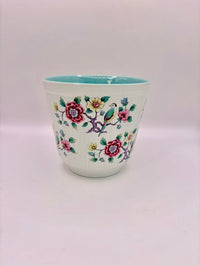 Ceramic cup with floral and bird design on a white background
