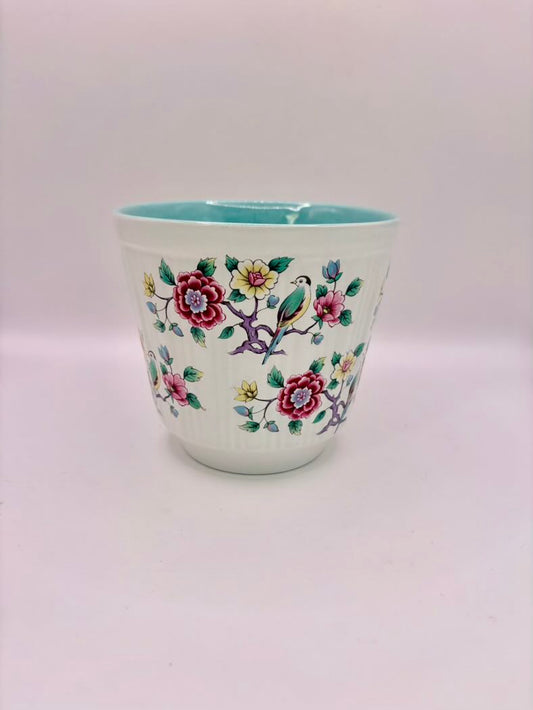 Ceramic cup with floral and bird design on a white background