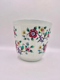 Ceramic cup with floral and bird design on a white background