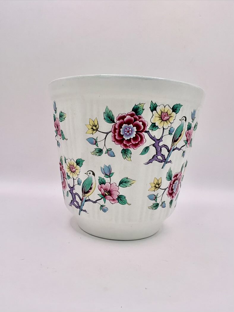 Ceramic cup with floral and bird design on a white background