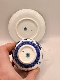 Hand holding a small ceramic container with blue and white design on a plain background