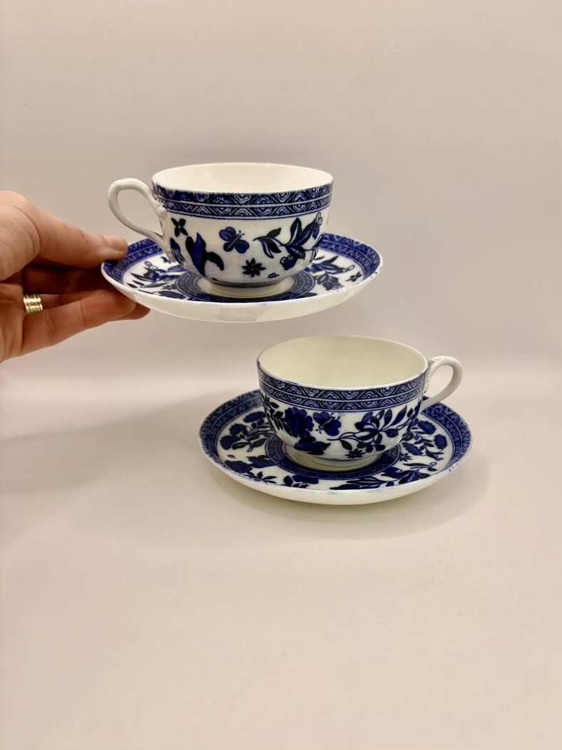Two blue and white teacups with saucers on a beige surface.