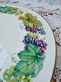 Decorative plate with painted grapes and leaves on a lace tablecloth