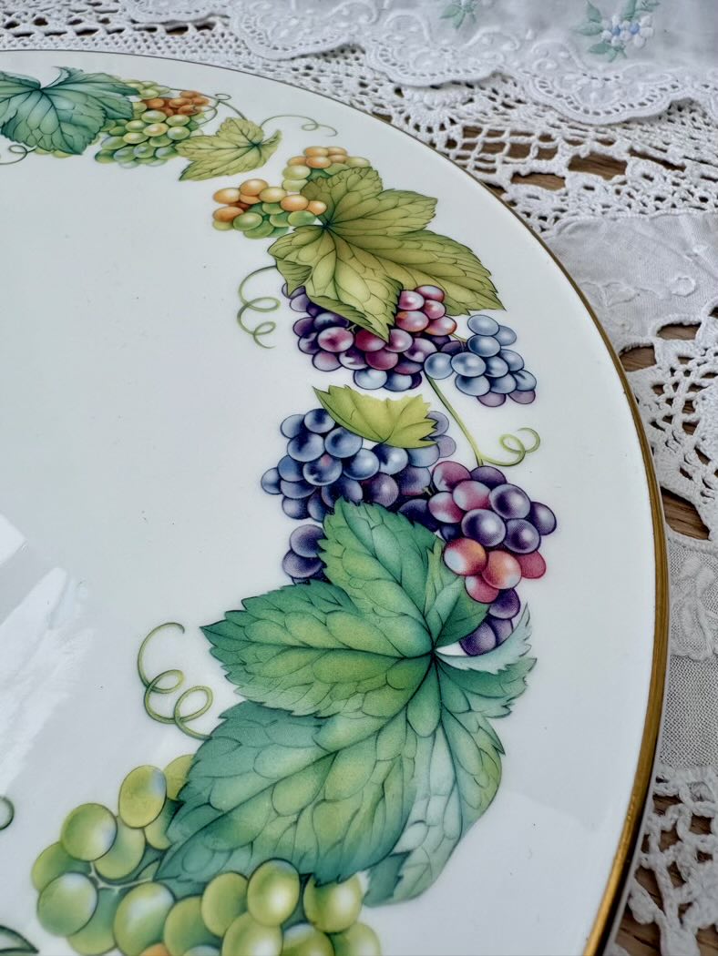 Decorative plate with painted grapes and leaves on a lace tablecloth