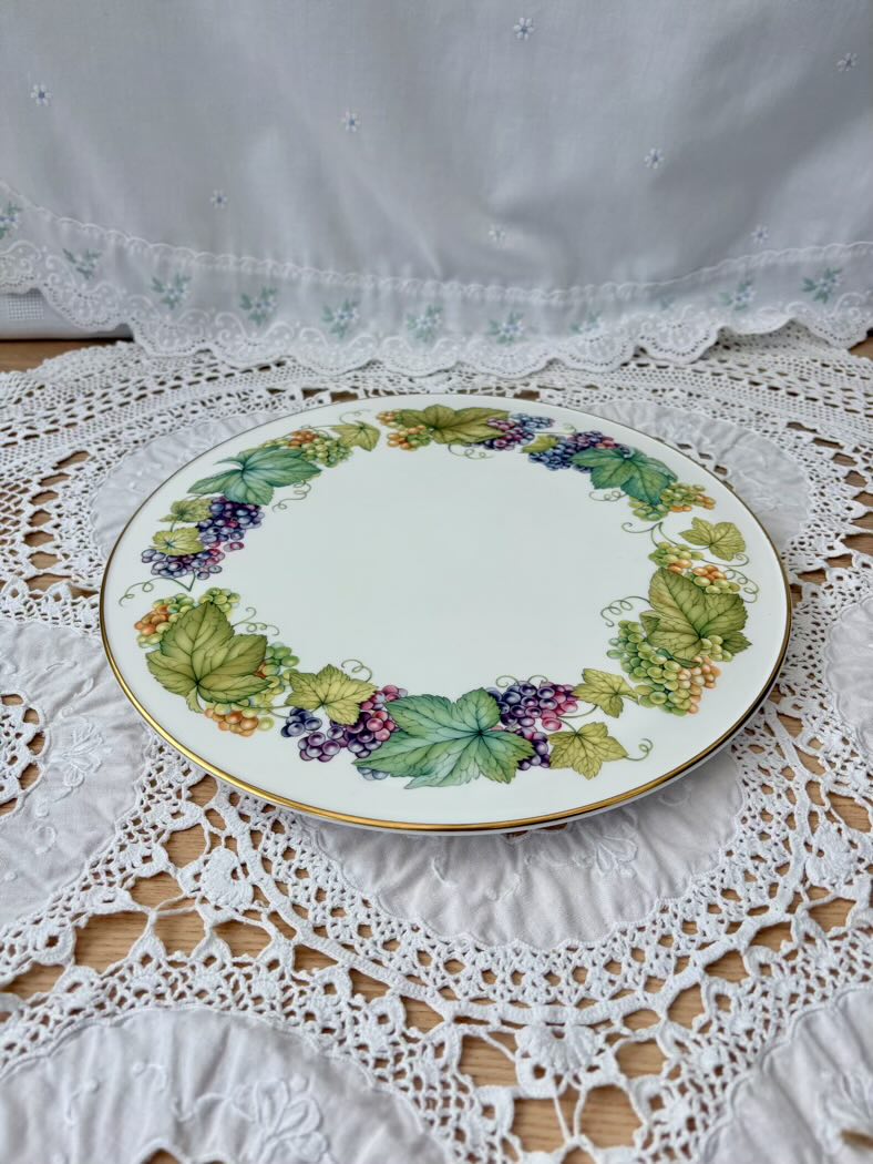 Decorative plate with floral and grape design on a lace tablecloth
