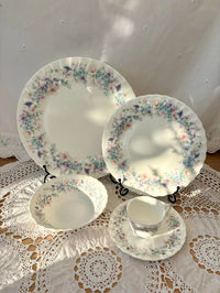 Set of floral-patterned ceramic dishes on a lace tablecloth