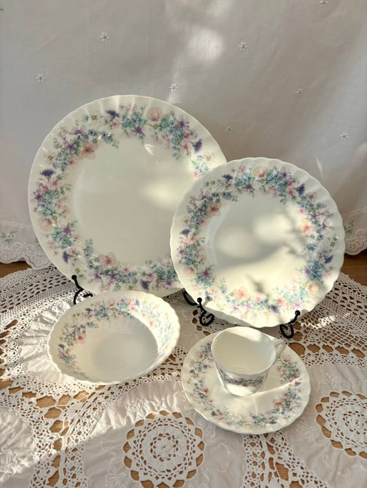 Set of floral-patterned ceramic dishes on a lace tablecloth