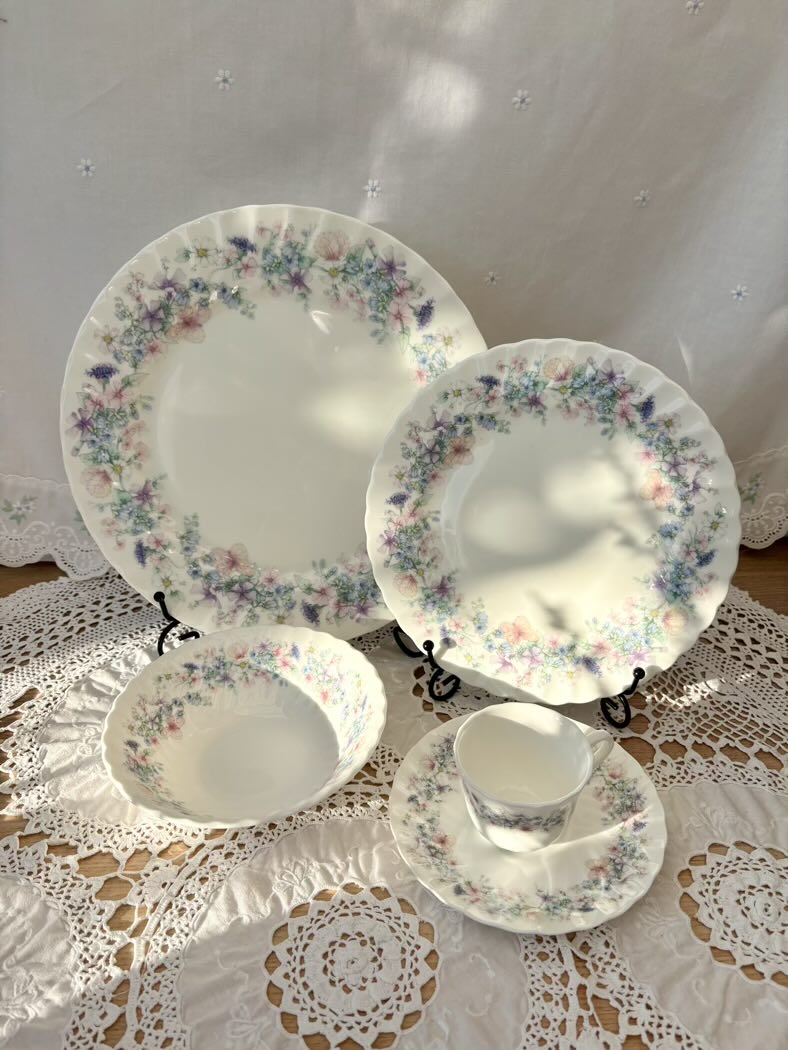 Set of floral-patterned ceramic dishes on a lace tablecloth