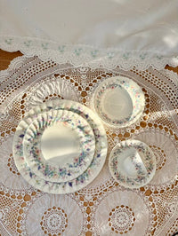 Set of floral-patterned ceramic plates on a lace tablecloth