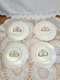 Four decorative plates with intricate designs on a lace tablecloth.