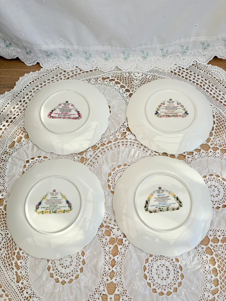 Four decorative plates with intricate designs on a lace tablecloth.