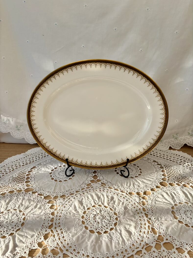 White oval plate with gold rim on a lace tablecloth
