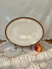 Decorative white plate with gold rim on a lace tablecloth with an apple beside it.