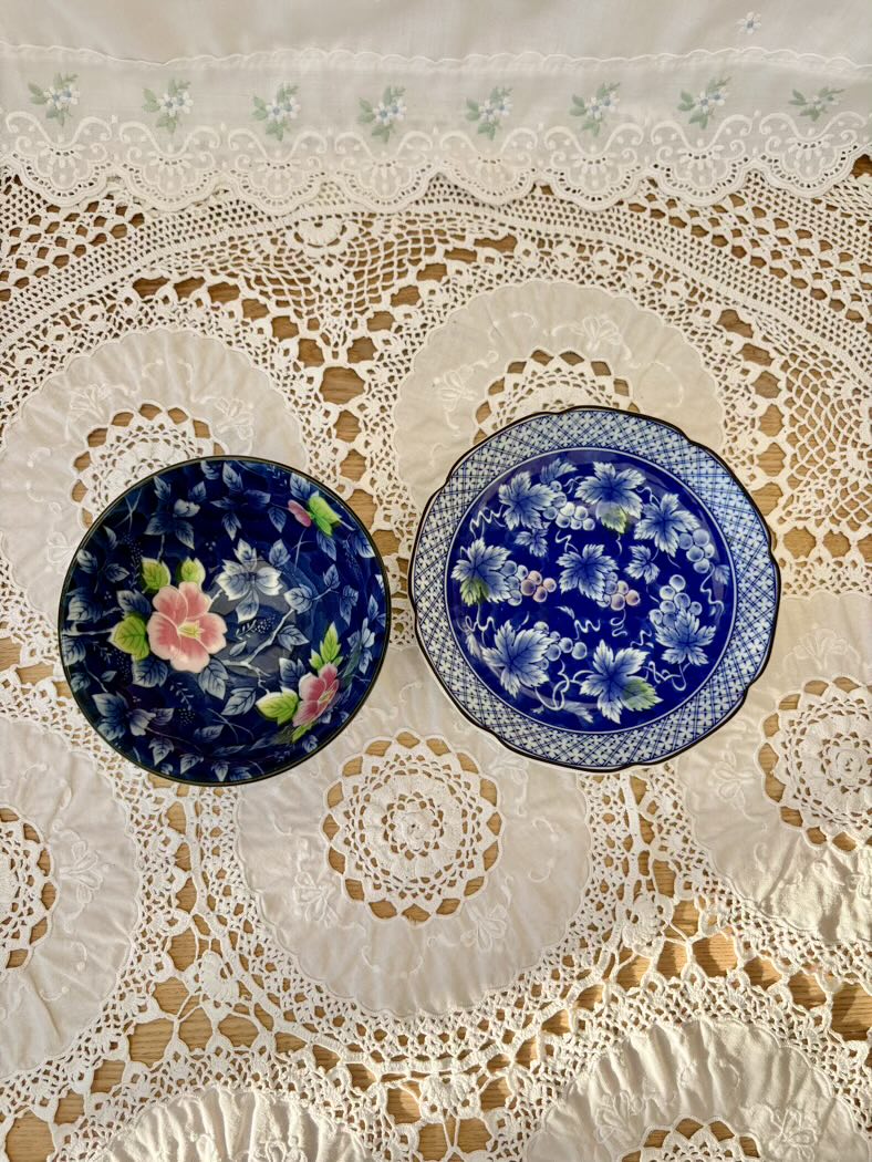 Two floral-patterned plates on a lace tablecloth