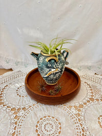 Decorative ceramic vase with air plant on a wooden tray on a lace tablecloth