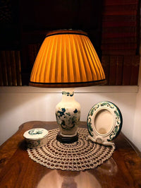 Lamp with pleated shade on a wooden surface with decorative items