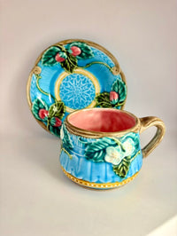 Decorative ceramic cup and saucer with floral patterns on a beige background