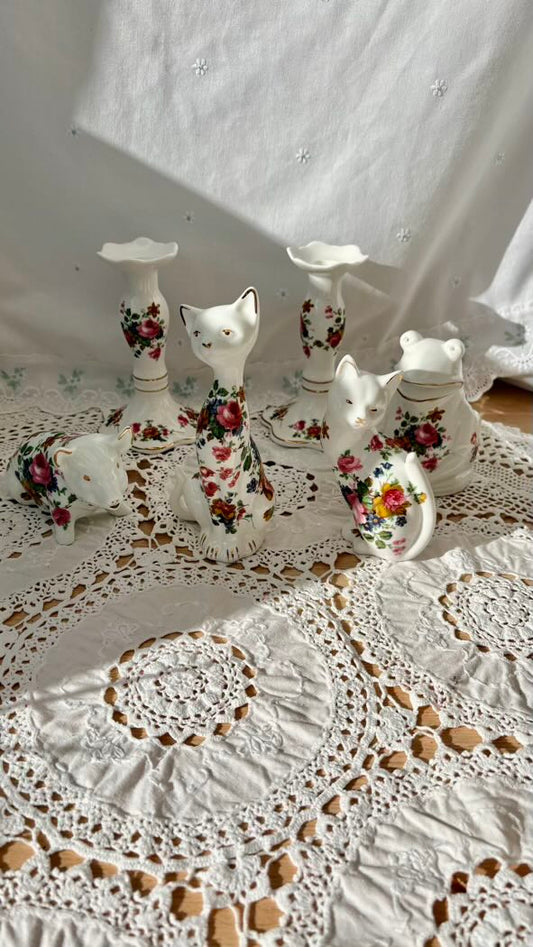 Decorative ceramic cats with floral patterns on a lace tablecloth