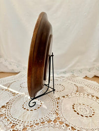 Wooden plate on a stand with a white lace tablecloth in the background