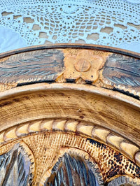 Close-up of a decorative ceramic plate with intricate patterns on a textured surface.