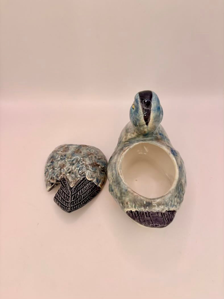 Ceramic duck-shaped container with lid on a light pink background