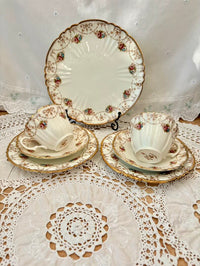 Vintage-style ceramic tea set with floral patterns on a lace tablecloth.