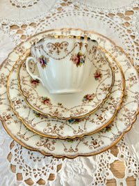 Vintage teacup and saucers with floral patterns on a lace tablecloth