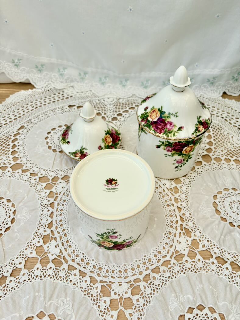 Decorative ceramic canisters with floral designs on a lace tablecloth