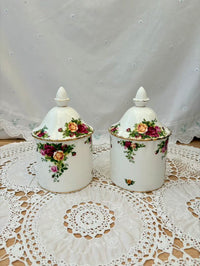 Two ceramic jars with floral designs on a lace doily