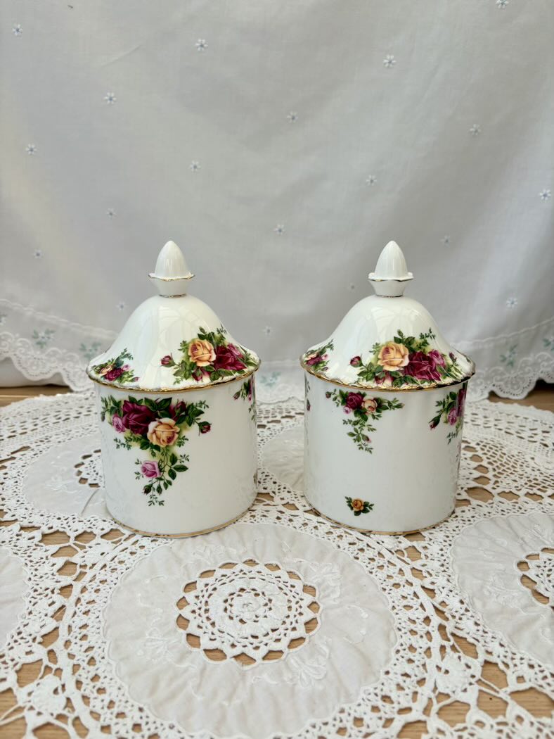 Two ceramic jars with floral designs on a lace doily