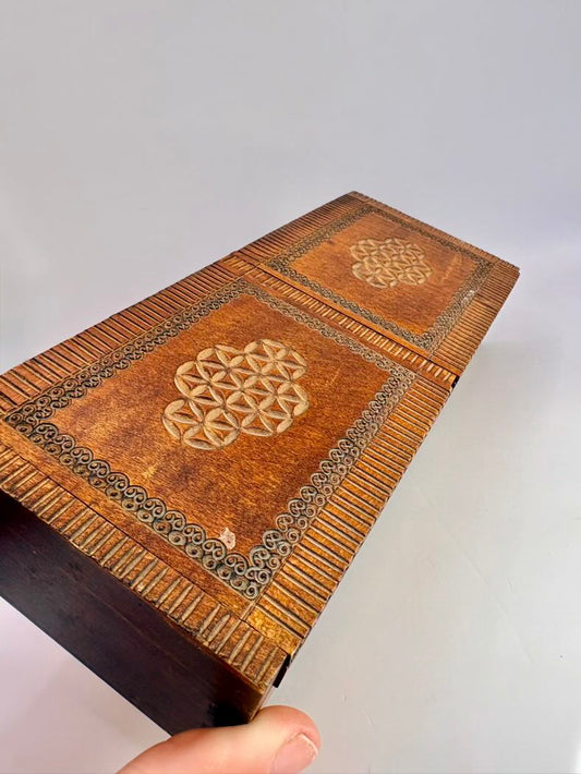 Decorative wooden box with intricate carvings on a plain background