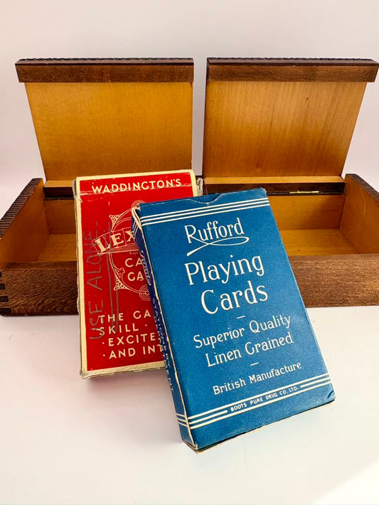 Two playing card boxes, one red and one blue, with a wooden box in the background.