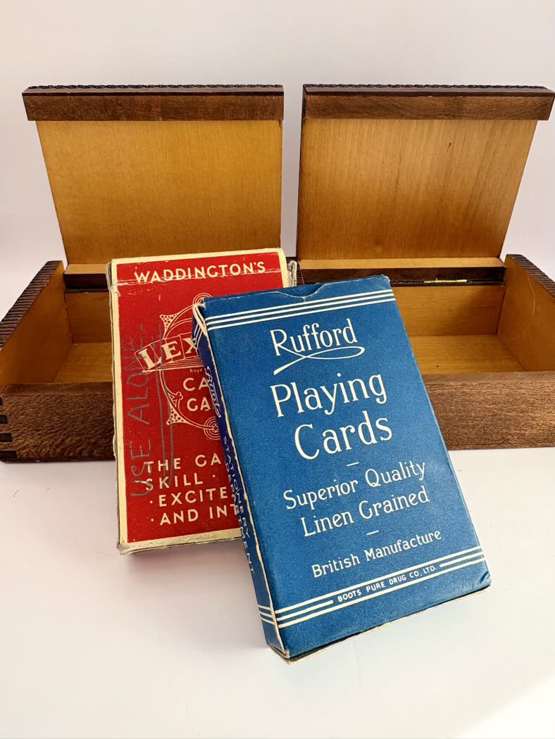 Two playing card boxes, one red and one blue, with a wooden box in the background.