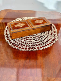 Wooden jewelry box with intricate designs on a doily