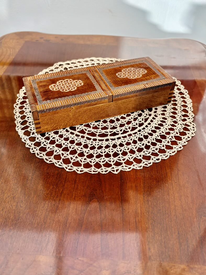 Wooden jewelry box with intricate designs on a doily