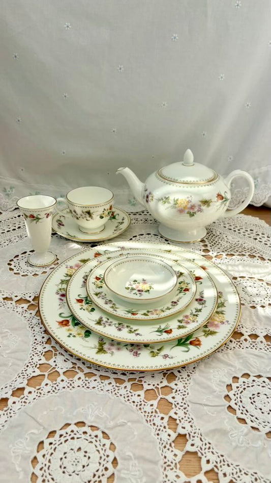 Vintage ceramic tea set with floral patterns on a lace tablecloth.