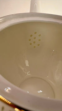 Close-up of a white ceramic pot with a lid on a light background