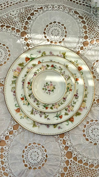 Set of decorative plates with floral patterns on a lace tablecloth.