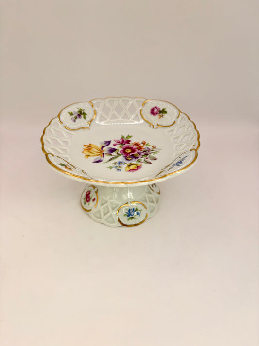 Decorative ceramic pedestal with floral design on a light pink background