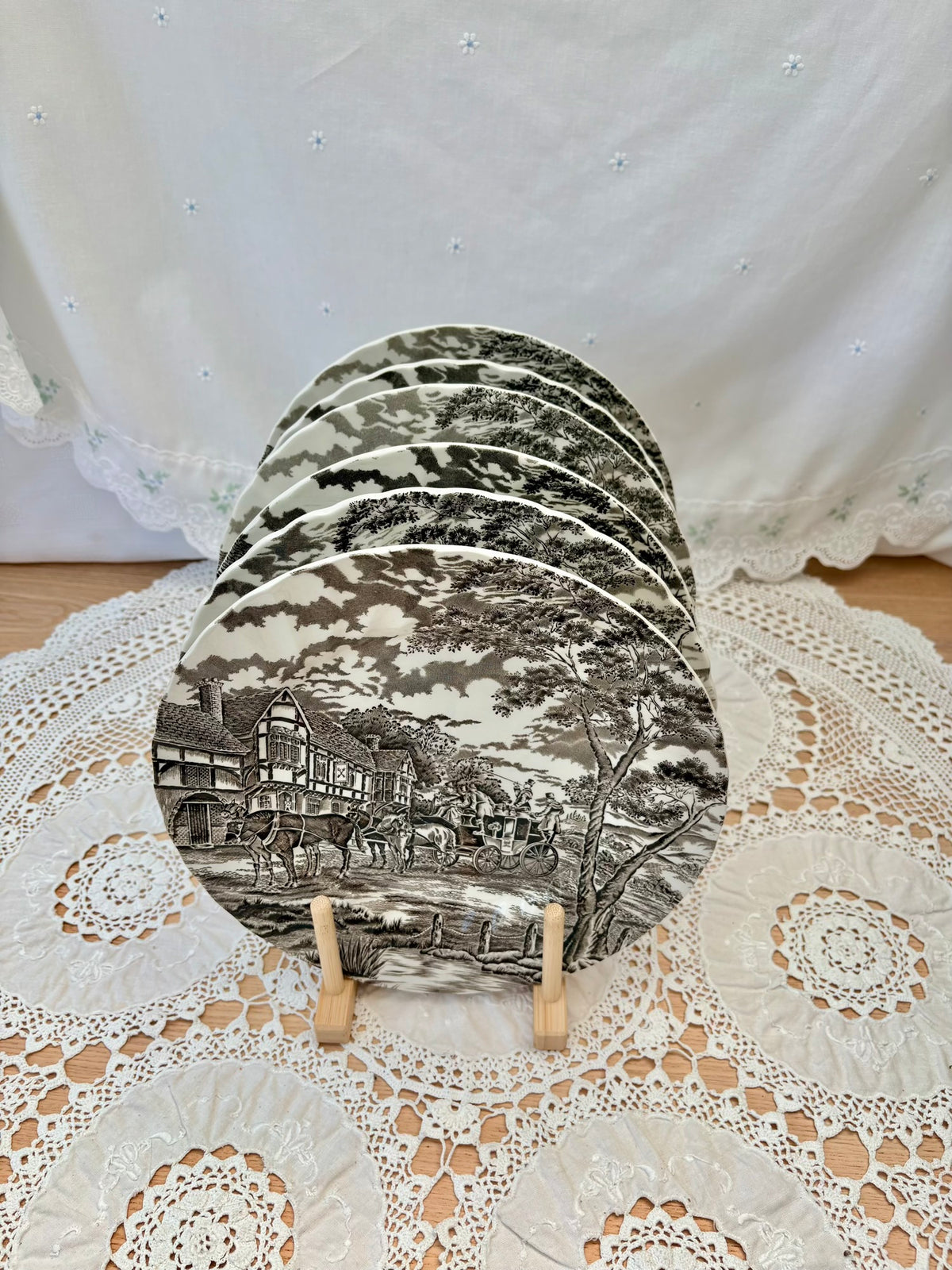 Set of six black and white ceramic coasters on a decorative stand with a lace tablecloth background.
