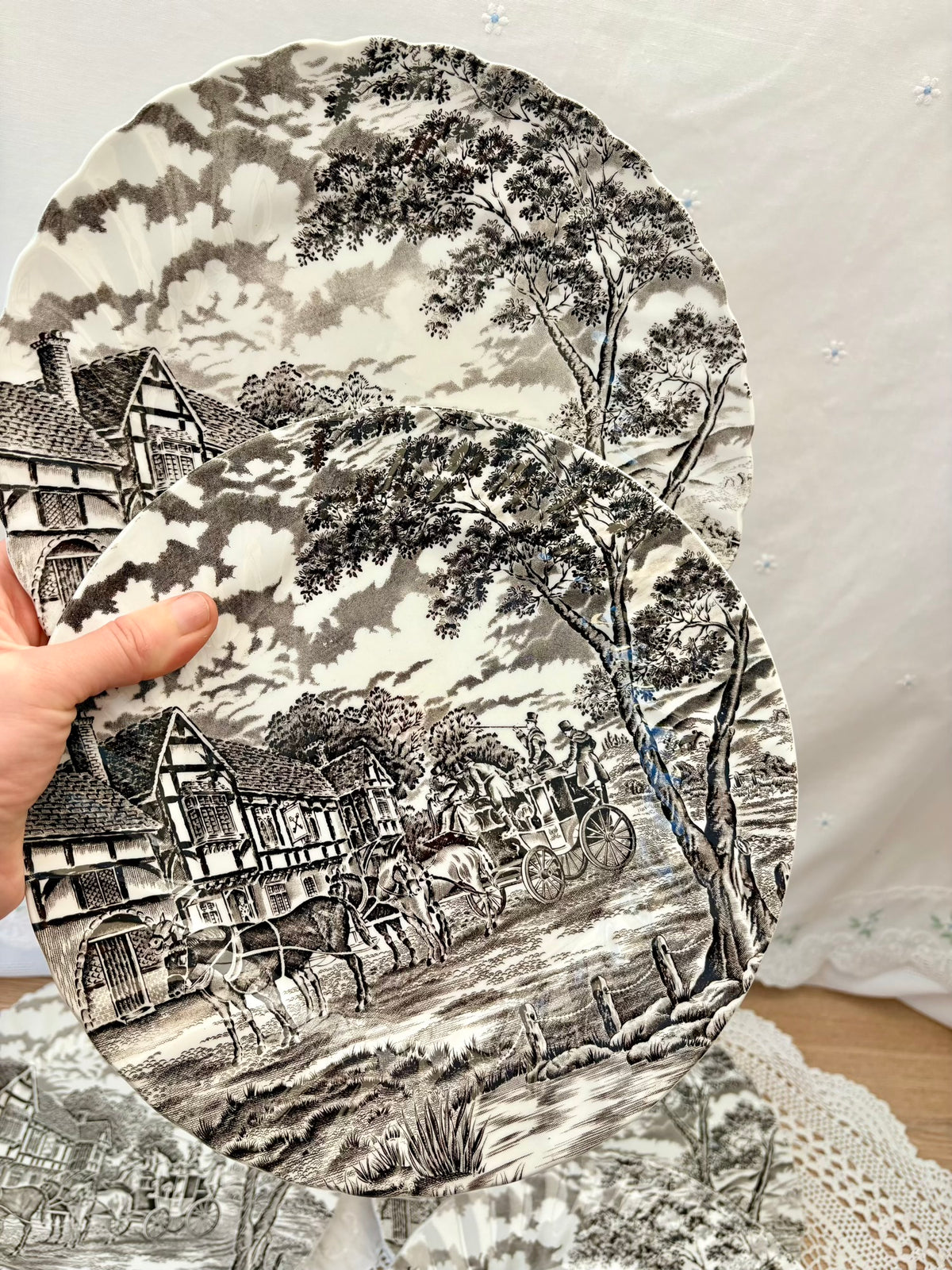 Decorative plate with a black and white landscape design featuring houses and trees.