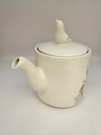 White ceramic teapot with lid on a light gray background
