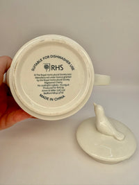 White ceramic teapot with a bird design on a beige background