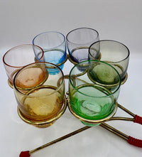 Set of colorful glass tumblers on a stand with a white background