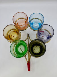 Set of colorful glass tumblers on a stand with a white background