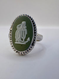 Silver ring with a green stone featuring an engraved design on a white background