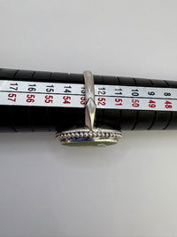 Silver ring with beaded design on a measuring tape for size reference