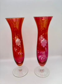Two red glass vases with floral patterns on a white background