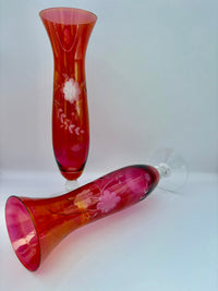 Two red glass vases with floral designs on a white background